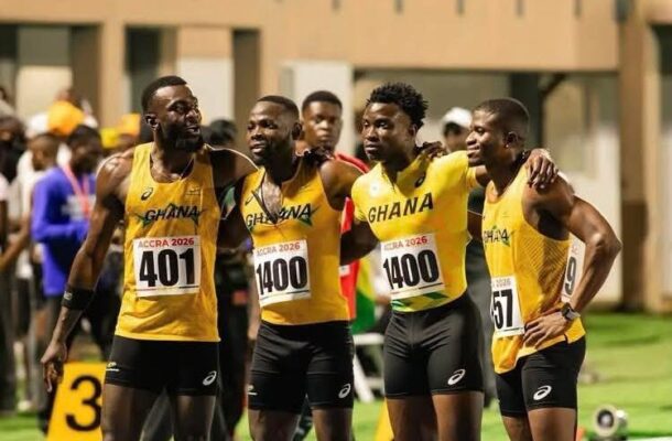 IMG_0565 | Ghanaguardian.com Four Ghanaian male runners in yellow, black shorts, with their arms around each other after a race, posing on a track with bib numbers 401 and 1400 visible.