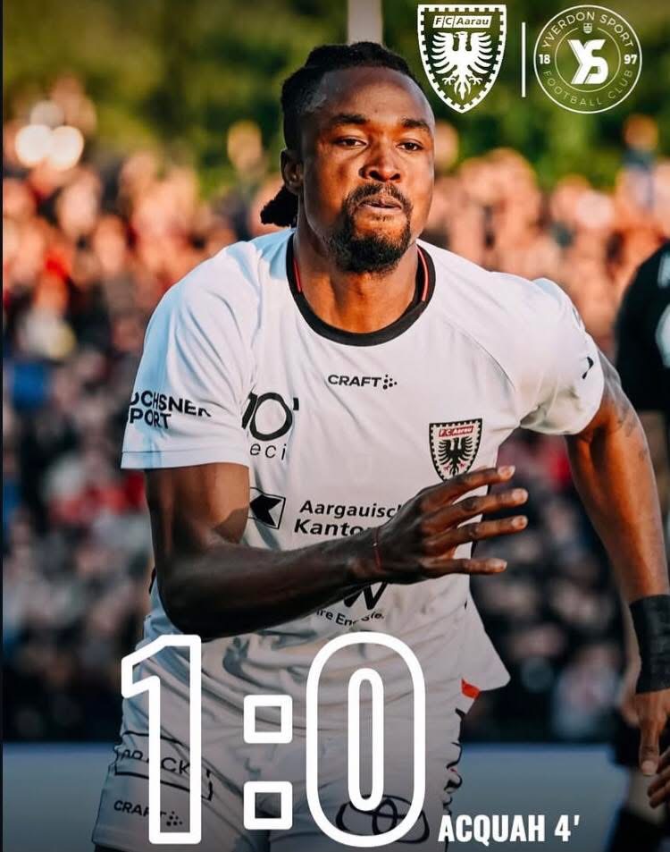 Male soccer player in a white jersey sprinting on a crowded field, focus on his determined expression; foreground shows a large 1:00 and ACQUAH 4' overlay, background spectators blurred.