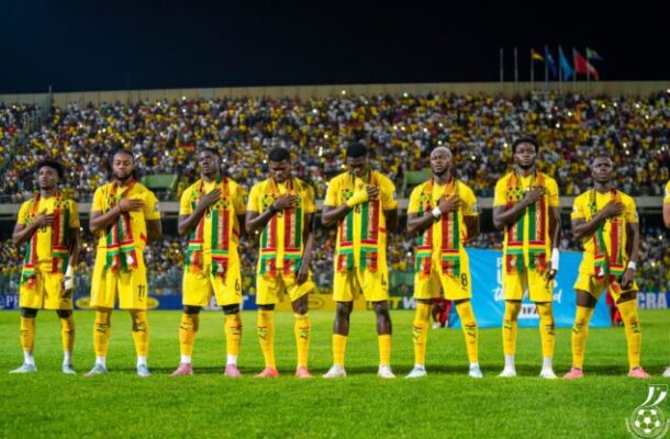 Senegal national football team in yellow kits stands in a line on the field with hands over their hearts before a match.