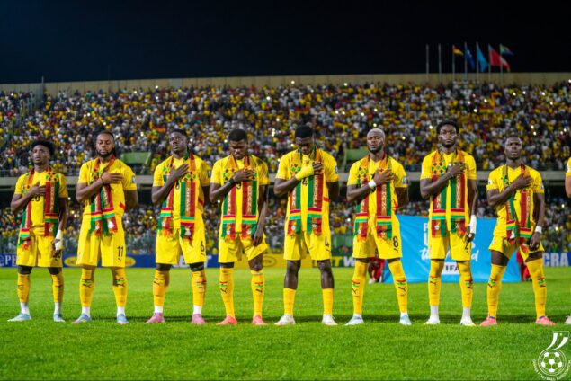 Senegal national football team in yellow kits stands in a line on the field with hands over their hearts before a match.