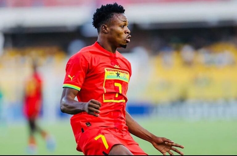 Soccer player in a red jersey with the number 7, running on a grassy field during a match.