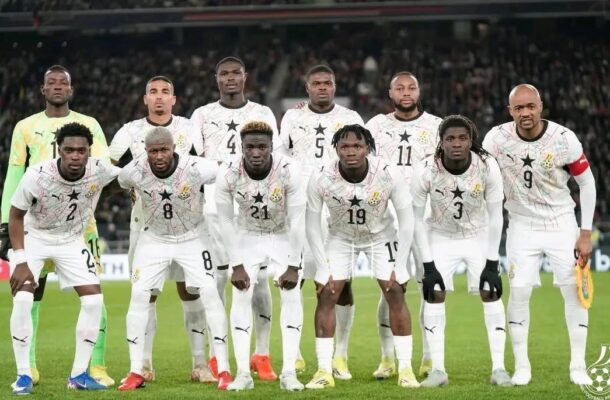 Ghana national football team posing for a group photo on the field in white jerseys with black stars.