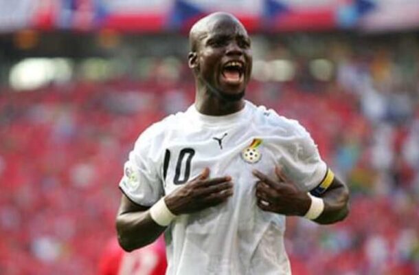 Football player in a white jersey with number 10 celebrates a goal, hands on chest, shouting with joy on the field.