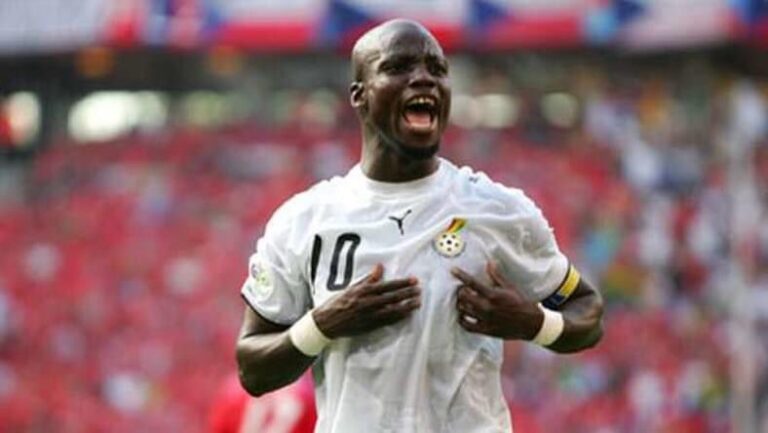 Football player in a white jersey with number 10 celebrates a goal, hands on chest, shouting with joy on the field.