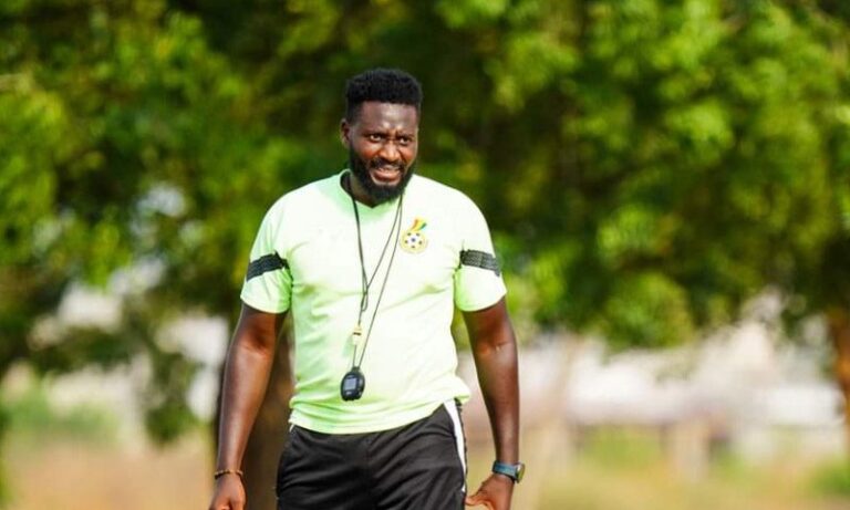 Athletic man in a neon green shirt with a whistle around his neck, standing outdoors and smiling.
