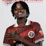 Portrait of Linda Owusu Ansah smiling, wearing a maroon Toronto FC jersey with a cross necklace and hands gently clasped in front.