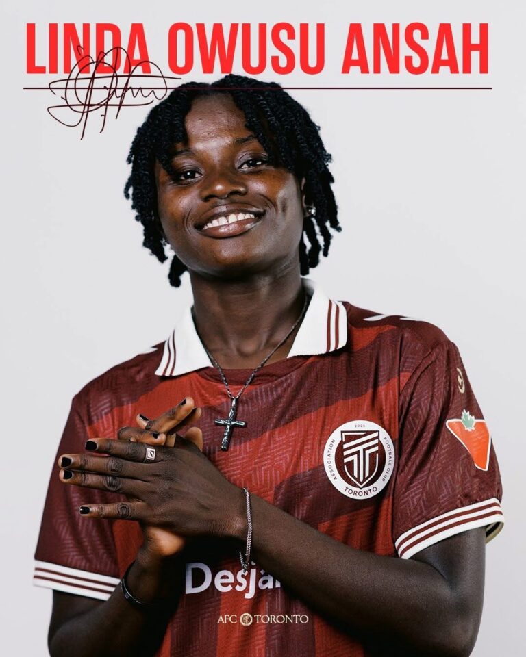 Portrait of Linda Owusu Ansah smiling, wearing a maroon Toronto FC jersey with a cross necklace and hands gently clasped in front.