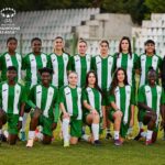 Women's soccer team in green and white striped kits posing on a field with stadium seats in the background; UEFA Women's Champions League logo visible on the image.