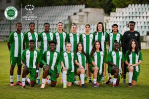 Women's soccer team in green and white striped kits posing on a field with stadium seats in the background; UEFA Women's Champions League logo visible on the image.