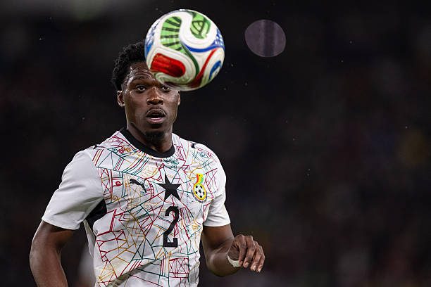 Soccer player in a white geometric-pattern jersey with the number 2, watching an airborne ball during a match.