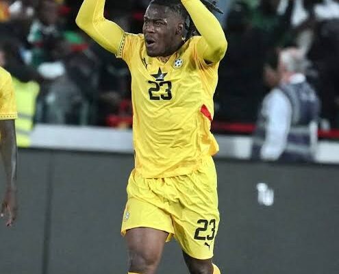 Soccer player in yellow jersey #23 celebrating with arms raised on the field, crowd in background