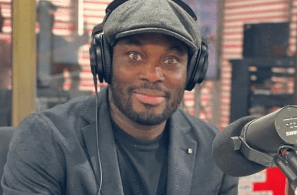 IMG_0759 | Ghanaguardian.com Smiling man in a gray flat cap and blazer wearing over-ear headphones, seated at a radio studio microphone.