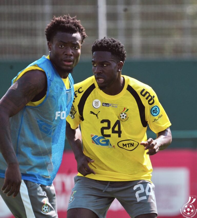 Two male soccer players training on a field, one in a yellow jersey (#24) and the other in a blue bib, facing each other closely.