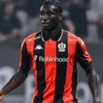 Soccer player in a red-and-black striped jersey with Robinhood sponsor, running on the field during a match.