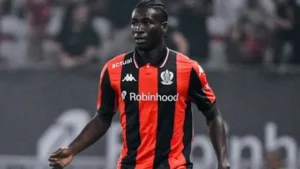 Soccer player in a red-and-black striped jersey with Robinhood sponsor, running on the field during a match.