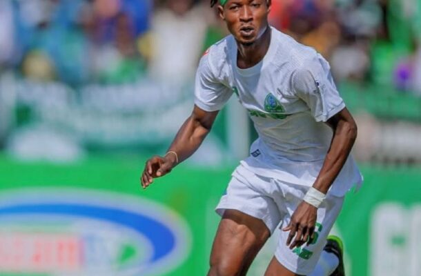 IMG_0802 | Ghanaguardian.com Soccer player in white kit with a green headband sprinting on a field with a blurred crowd in the background.