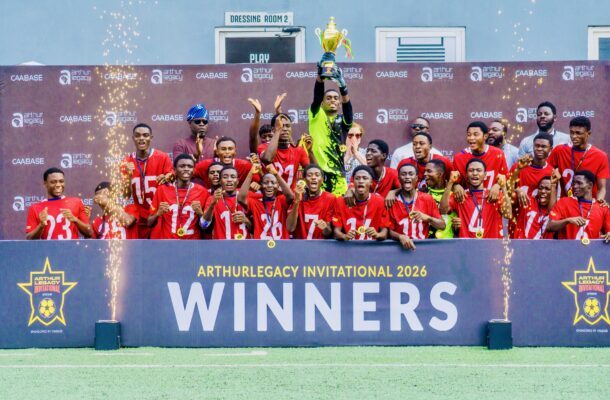 IMG_1287JPG | Ghanaguardian.com Group of young soccer players in red jerseys celebrate on stage, holding medals and a trophy aloft at an awards ceremony.