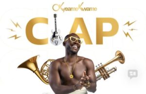 Smiling Black man with gold jewelry, shirtless, surrounded by brass instruments (trumpet, trombone) and a guitar, with a large gold 'CAP' in the background.