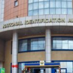Front of a government building labeled 'National Identification Authority' with tall columns and a curved entrance, blue and beige exterior.