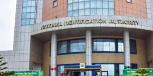Front of a government building labeled 'National Identification Authority' with tall columns and a curved entrance, blue and beige exterior.