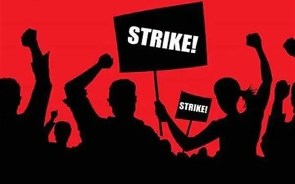 Silhouetted protesters raise fists and carry signs that read STRIKE against a bold red background, conveying a labor strike demonstration.
