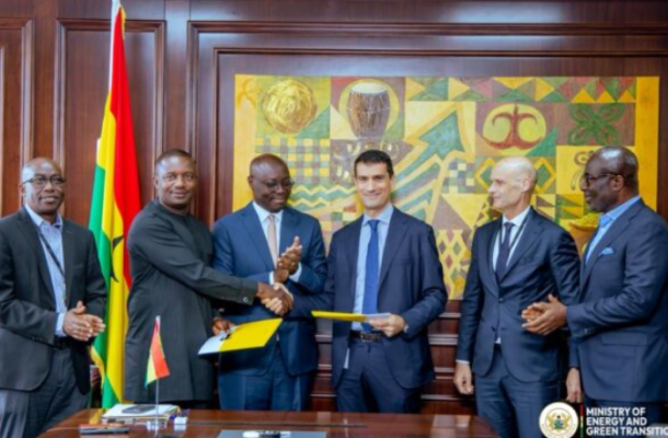 Screenshot-2026-05-05-170414 | Ghanaguardian.com Six men in suits participate in a formal signing ceremony: two center figures shake hands and exchange documents, with a flag behind them and an official crest in the corner.