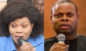 Two people speak into handheld microphones: a woman with a large curly hairstyle in a blue top on the left and a man in a black shirt on the right, both addressing an audience.