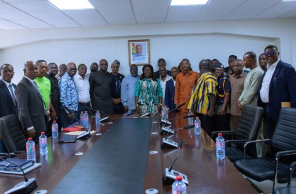 Group of professionals standing in a boardroom around a long conference table for a formal meeting in session.