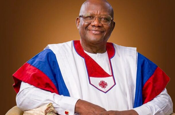 WhatsApp Image 2026-05-25 at 061354 | Ghanaguardian.com Smiling older man in white ceremonial attire with red and blue accents, seated against a brown gradient backdrop.