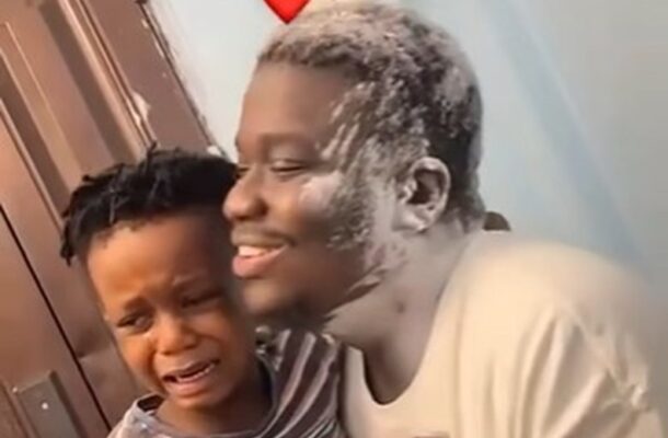 A smiling man comfortingly hugs a crying child near a door, with a red heart emoji above the man's head.