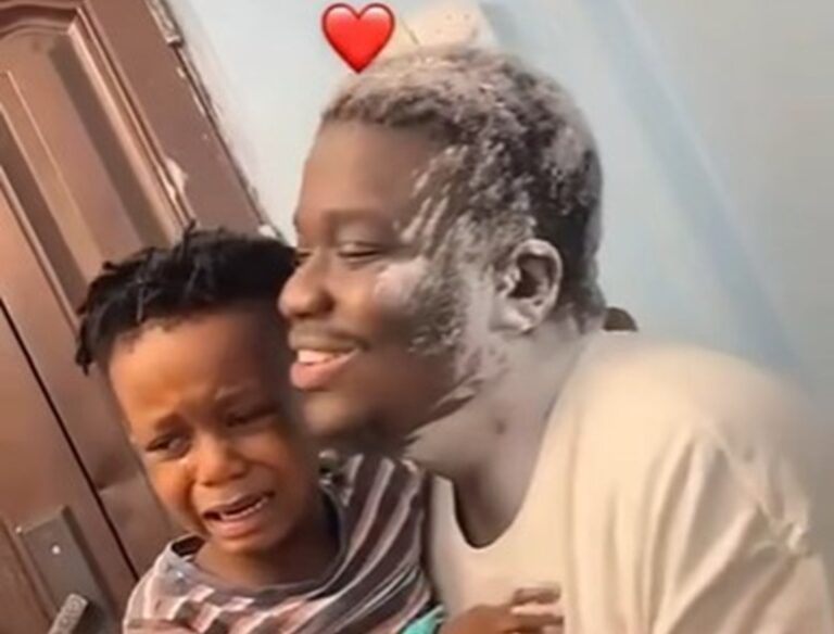 A smiling man comfortingly hugs a crying child near a door, with a red heart emoji above the man's head.
