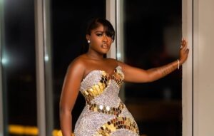 Woman in a silver and gold sequined gown posing by a doorway at night.