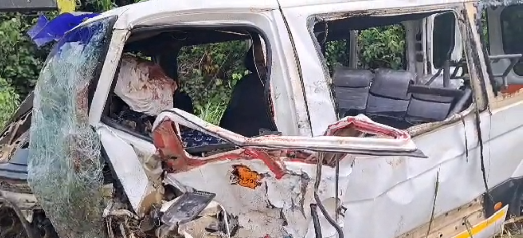 White van with extensive front-end damage from a crash; shattered windshield and exposed interior seats.
