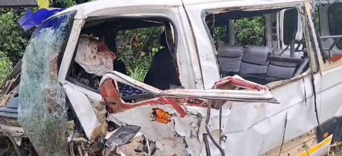 Severely damaged white van after a collision; shattered windshield, crumpled front end, exposed interior.
