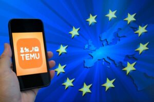 Hand holding a smartphone displaying the TEMU app logo against a blue background with EU stars and a Europe map motif