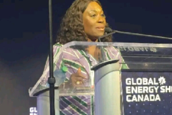 19975283 | Ghanaguardian.com Woman speaking at a clear podium during the Global Energy Show Canada, wearing a striped purple and green blouse.