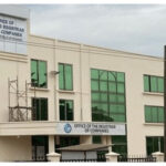 Two-story government building with signs reading 'Office of the Registrar of Companies' and green-tinted windows.