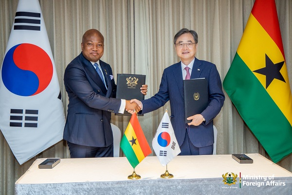 94093039 | Ghanaguardian.com Two diplomats in suits shake hands over a table after signing an agreement; Ghana and South Korea flags on the table and a backdrop of curtains behind them.