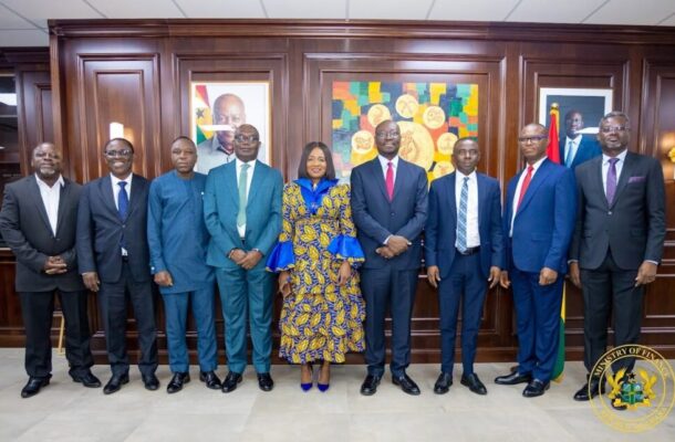 Audit-Board-1024x642 | Ghanaguardian.com Nine professionals in formal attire pose for a group photo in a wood-paneled government office; woman in a blue and gold patterned dress stands center.
