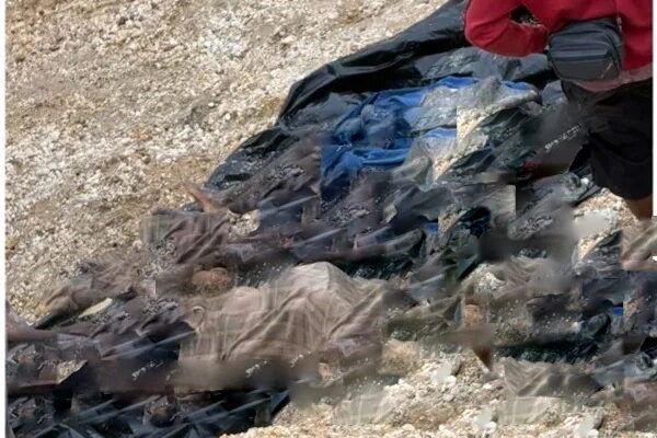 Galamseyers2 | Ghanaguardian.com Person in a red jacket stands near a pile of dark clothing or tarps spread on rocky ground.