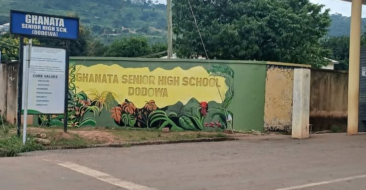 Green wall mural at Ghanata Senior High School, Dodowa, with tropical plants and the school name; blue signboard with the same name stands to the left.