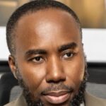 Close-up portrait of a man with a short beard, looking slightly to the left.