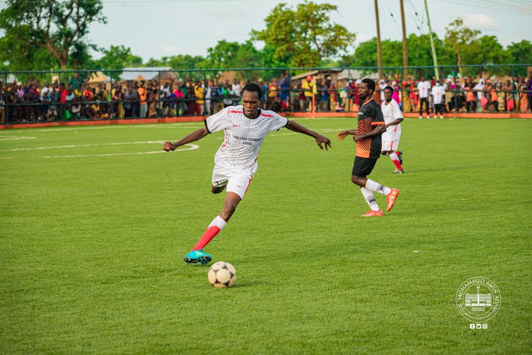 IMG-20260608-WA0004 | Ghanaguardian.com Soccer player in a white kit kicks the ball on a green field as a crowd watches from behind a fence.
