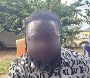 Man with dreadlocks and a blurred face wearing a black-and-white patterned shirt outdoors.