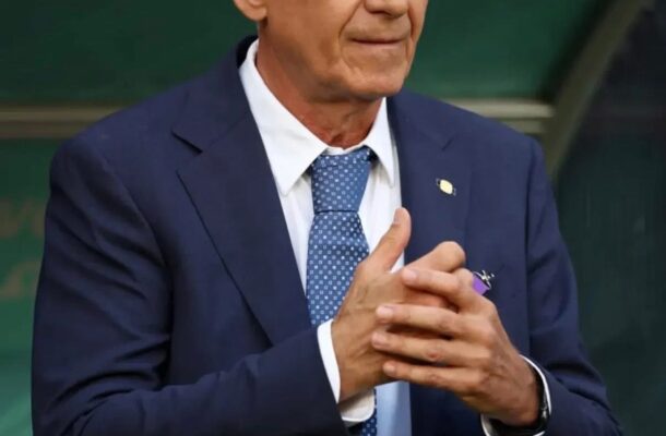 IMG_0672 | Ghanaguardian.com Middle-aged man in a navy suit and blue patterned tie, standing with hands clasped in front, on a green backdrop.