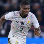 Soccer player in a white Ghana national team jersey with a colorful geometric pattern, sprinting on the field.