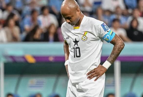 IMG_0827 | Ghanaguardian.com Soccer player in white jersey with number 10 stands with hands on hips on the field, stadium crowd in background, wearing captain's armband on left arm.