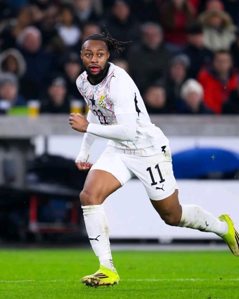 Soccer player in white kit with number 11 sprinting on the green field during a match.