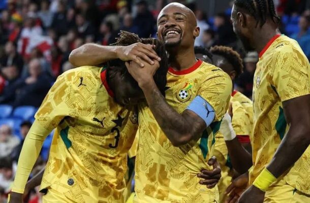 Ghana national football team players celebrate on the field, embracing and smiling after a goal.