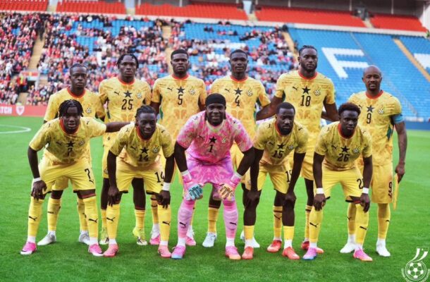 IMG_0856 | Ghanaguardian.com Soccer team in yellow uniforms poses for a pre-match photo on a green field with stands full of fans in the background; goalkeeper wearing pink in front center.